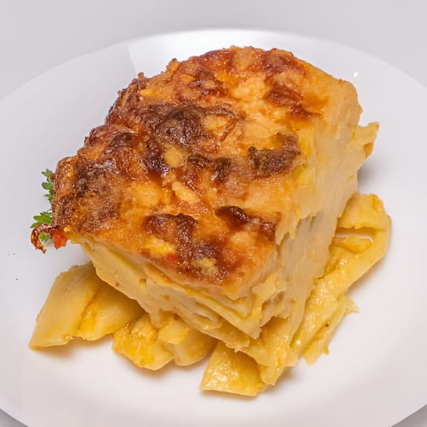 A golden-brown baked Haitian gratin dish, possibly plantain or potato, served on a white plate.