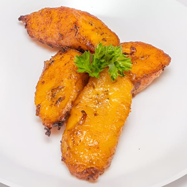 Four golden-brown fried plantains, or bannann peze, garnished with fresh parsley on a white plate.